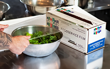 Chef using foodservice film to package fresh spinach